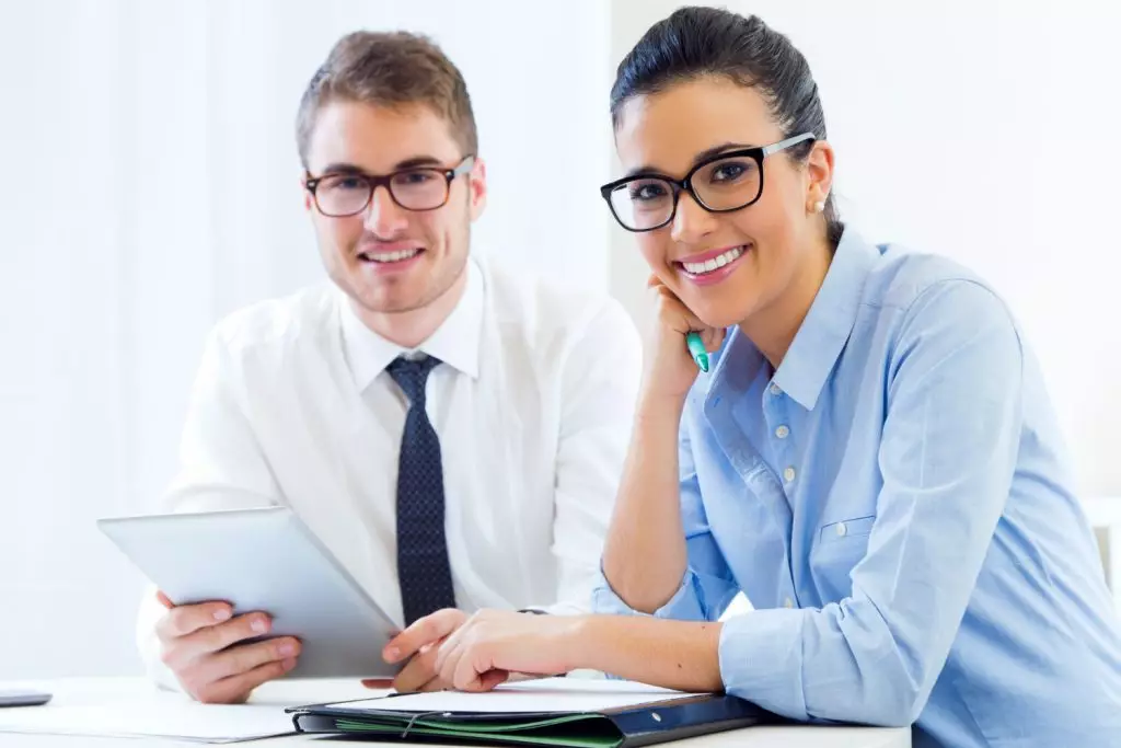 um homem de camisa branca e gravata preta, com uma mulher de camisa azul claro, testando o software para advogados GOJUR