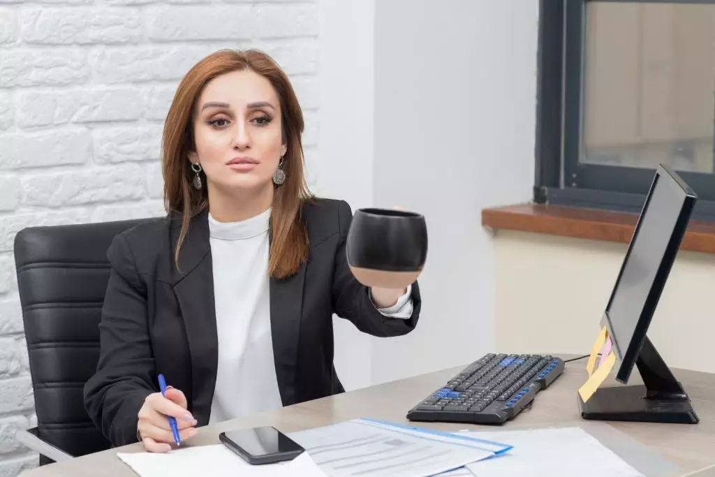 Foto de mulher sentada em frente ao computador com caneca em mãos convidando para conhecer a advocacia do futuro