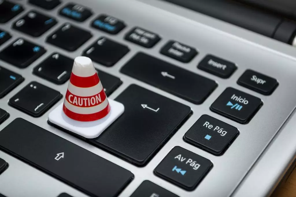 Foto de teclado com cone escrito "cautela" representando desafios do direito digital